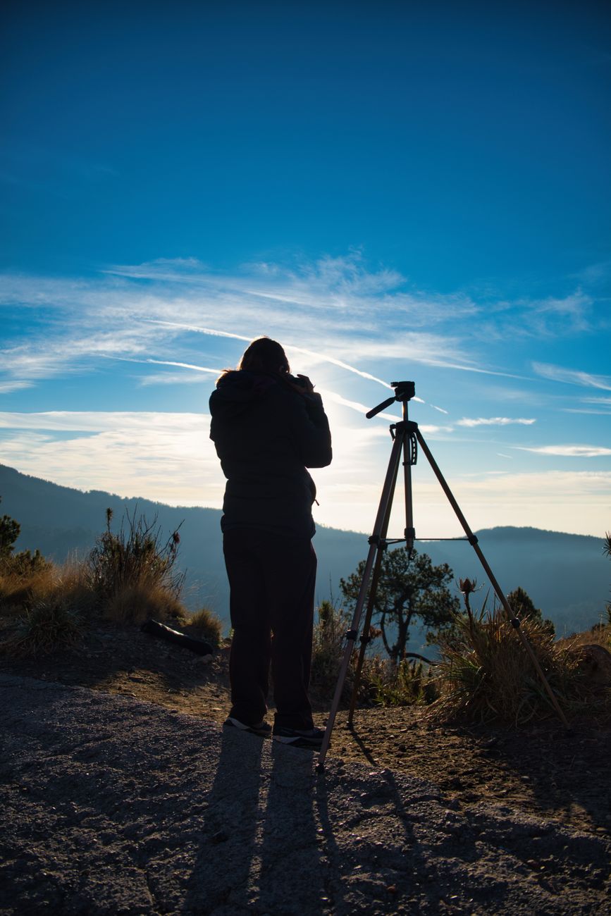 Solo traveler setting camera tripod on tranquil cliffside